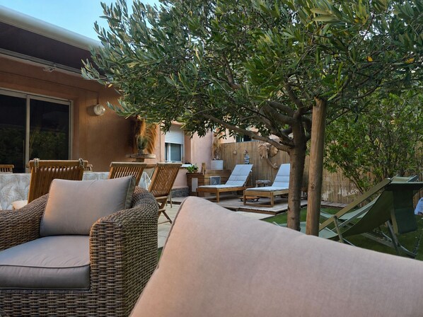 An outdoor seating area with wicker furniture and a tree providing shade. - Bastidon 50 m from the beach 2 bedrooms (Saint-Raphaël)