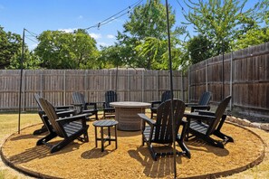 A backyard with a wooden fence, outdoor furniture, and string lights. - Luxury Poolside Retreat in DFW (North Richland Hills)