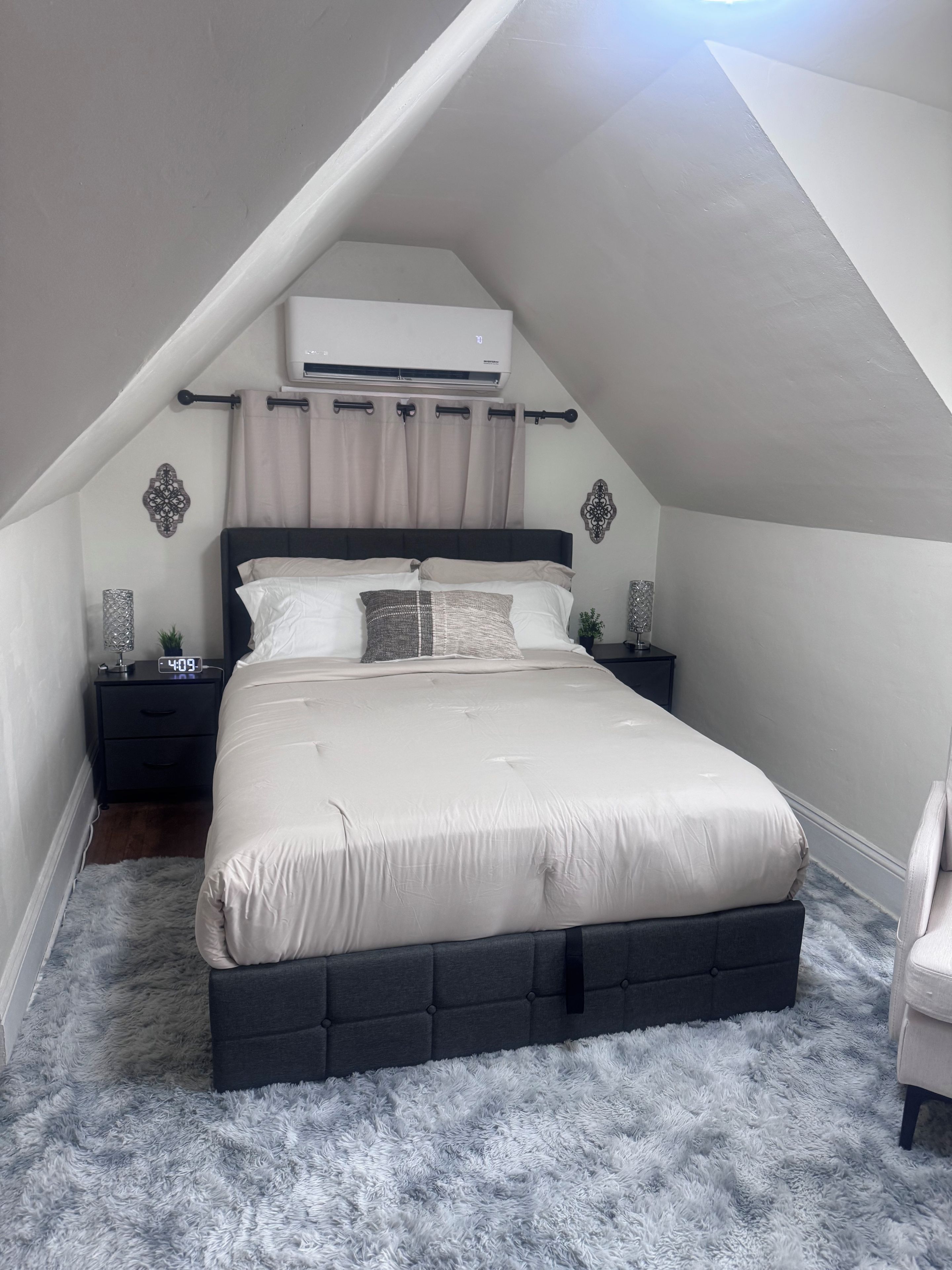 Une chambre à coucher avec un lit, des tables de chevet, un appareil de climatisation et un tapis moelleux.