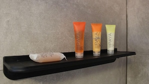 A black shelf with three tubes of Paya cream and a small packet on a textured wall. - Auberge Aux Quatre Matins (Saint-Côme)