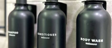Three black bottles of toiletries on a tiled wall.