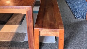 Un comedor con una mesa de madera y bancos, un muro de piedra y una chimenea negra.