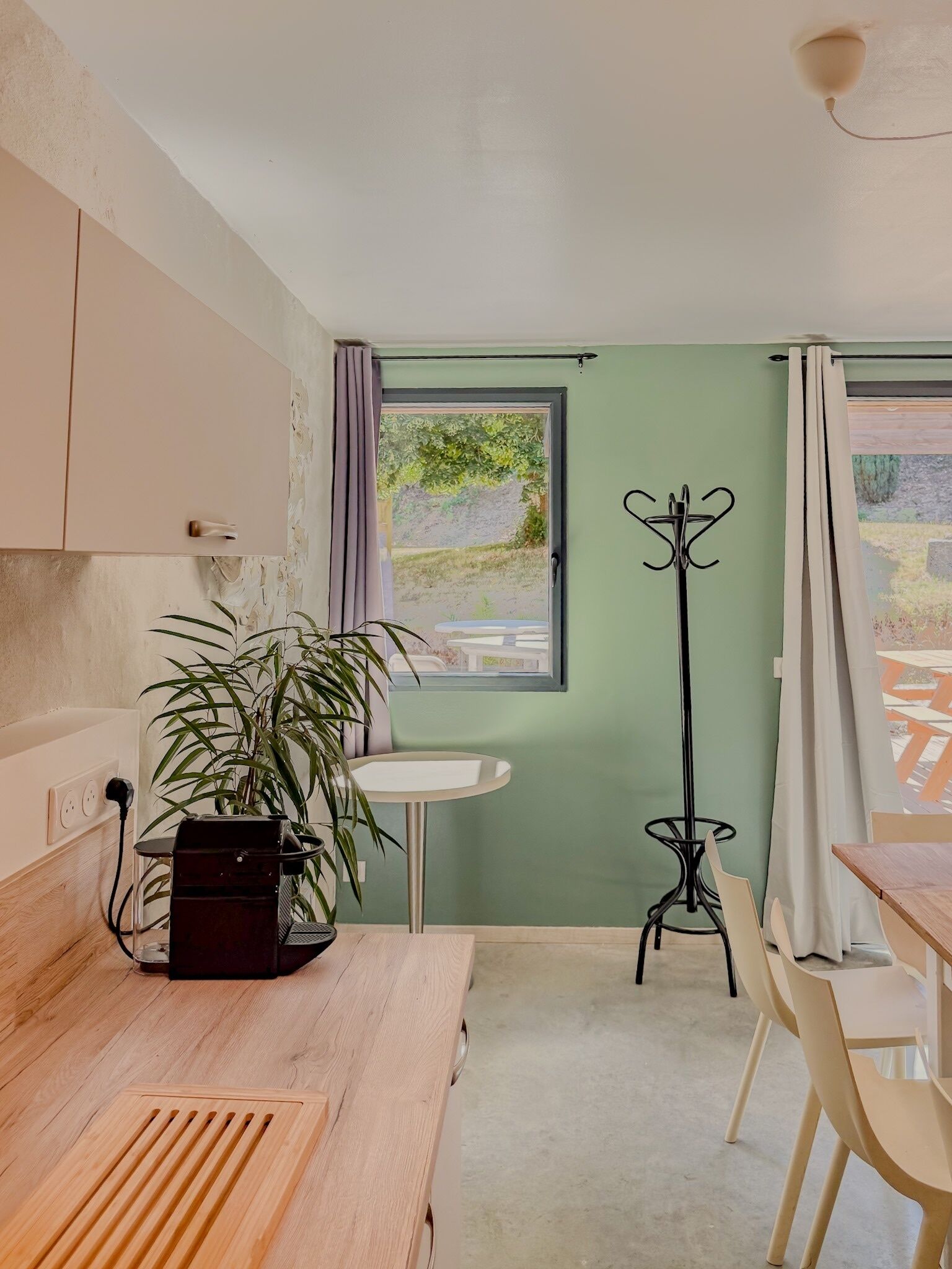 Une cuisine de taille réduite, avec une fenêtre, une petite table et un porte-manteau.