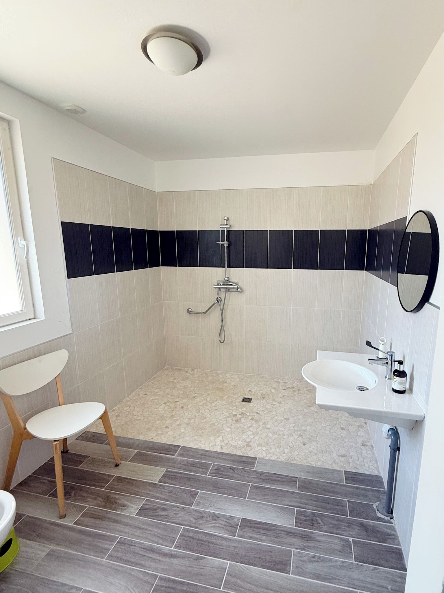 Une salle de bain moderne avec une douche, un lavabo et une chaise.