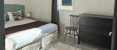 Un dormitorio con dos camas, un tocador, una silla, un ventanal y una decoración de sol en la pared.