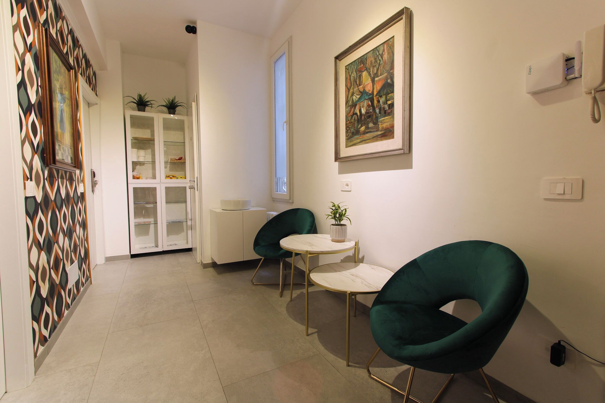 Um interior moderno com área de refeições, uma cadeira verde, uma pequena mesa e um armário com portas de vidro.
