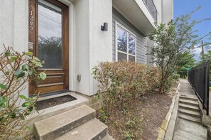 A residential building with a wooden front door, a mailbox, and a small garden area with steps leading up to the entrance. - Modern Heights Home. 5 min to Downtown. Pet Friendly. (Houston)