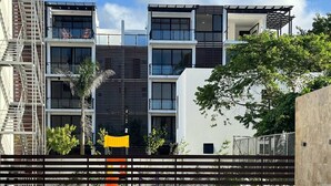 Un bâtiment moderne doté d’une piscine, d’une clôture en bois et d’un palmier.