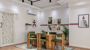 A modern dining area with a round wooden table, green upholstered chairs, and a patterned rug. - New Cairo Lush & Light (محافظة القاهرة‬)