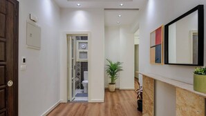 A hallway with wooden flooring, a door on the left, and a potted plant on the right. - New Cairo Lush & Light (محافظة القاهرة‬)