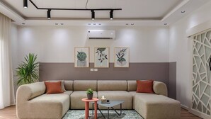 A modern living room with a sectional sofa, a small coffee table, and a potted plant. - New Cairo Lush & Light (محافظة القاهرة‬)