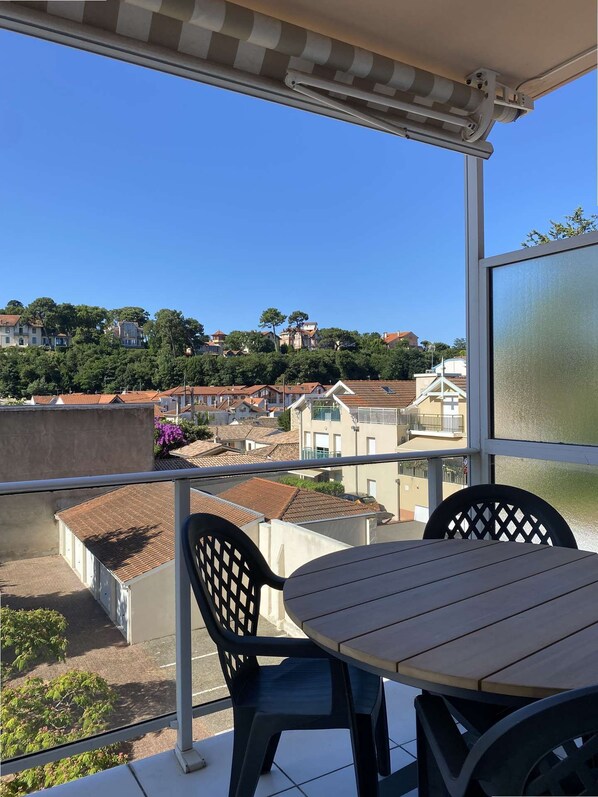 A balcony with a table and chairs, overlooking a residential area with houses and trees. - Renovated two-bedroom flat (55m²), south-facing balcony  et  parking – town centre (ARCACHON)