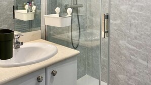A modern bathroom with a glass-enclosed shower, a white sink, and a mirror with lights. - Renovated two-bedroom flat (55m²), south-facing balcony  et  parking – town centre (ARCACHON)