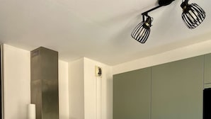 A modern kitchen with a central island, white cabinetry, a stainless steel range hood, and a built-in oven. - Renovated two-bedroom flat (55m²), south-facing balcony  et  parking – town centre (ARCACHON)