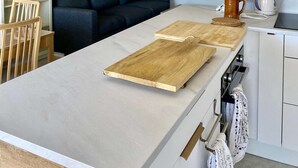 A modern kitchen with a central island, a sofa, and a dining area. - Renovated two-bedroom flat (55m²), south-facing balcony  et  parking – town centre (ARCACHON)