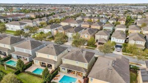Un barrio residencial con varias casas de dos plantas, cada una con jardín delantero y piscina.
