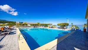 A swimming pool with lounge chairs, a view of the ocean, and a paved deck. - Beachfront with Rooftop Scenic Ocean View 2-bedroom (Saint Ann's Bay)