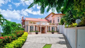 A large, two-story building with a red roof, a central entrance with a red door, and a paved driveway leading to the entrance.