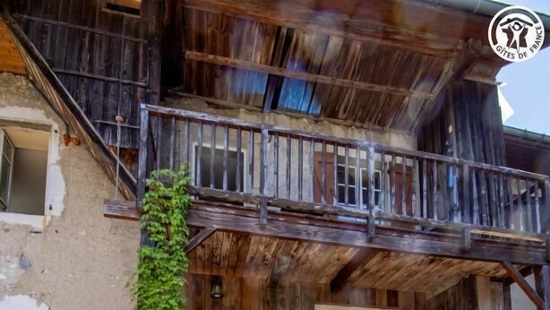 A rustic wooden building with a staircase leading to a door, surrounded by gravel and potted plants. - Gite ROSSANAZ - La compagnie du Bourg (LE CHATELARD)