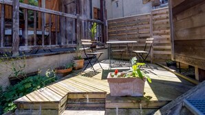 A wooden deck with a table and chairs, surrounded by potted plants and a wooden fence. - Gite ROSSANAZ - La compagnie du Bourg (LE CHATELARD)