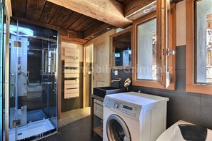 A compact, modern bathroom with a glass shower enclosure, a built-in washing machine, and a sink with a mirror. - Very comfortable studio for 2 people, living room with wood-burner, kitchen area with dishwasher, sl (Grimentz)