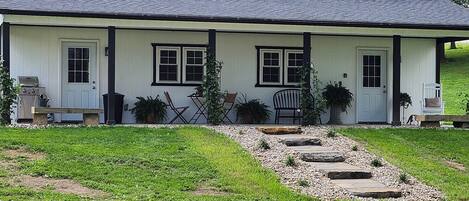 A two-story house with a front porch, a grill, and potted plants.