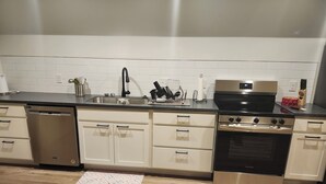 A modern kitchen with stainless steel appliances, white cabinetry, and a black countertop. - Brand new studio apartment with queen bed, queen pull out, WIFI and AC . (Wooster)