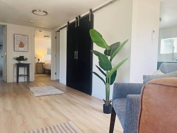A modern living room with a large sliding door, a potted plant, a blue sofa, and a wooden floor.