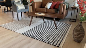 A living room with a brown leather sofa, a grey armchair, a coffee table, and a patterned rug.