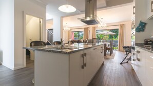 Una cocina moderna con una isla central, electrodomésticos de acero inoxidable y vistas al exterior.