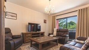 Una sala de estar moderna con sofás de cuero, una mesa de centro de madera, un televisor de pantalla plana y un gran ventanal con cortinas.