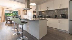 Cocina moderna con una isla central, taburetes de bar y electrodomésticos de acero inoxidable.