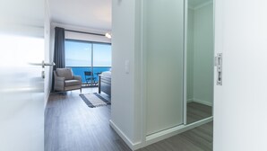 A modern hotel room with a large sliding glass door leading to a balcony with a view of the sea. - Blue Outlook Retreat by Atlantic Holiday (Água de Pena)