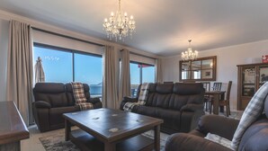 A spacious living room with leather sofas, a wooden coffee table, and a chandelier. - Blue Outlook Retreat by Atlantic Holiday (Água de Pena)