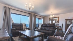 A modern living room with leather sofas, a wooden coffee table, and a chandelier. - Blue Outlook View by Atlantic Holiday (Água de Pena)