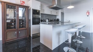 A modern kitchen with a central island, built-in oven, and stainless steel appliances. - Blue Outlook View by Atlantic Holiday (Água de Pena)