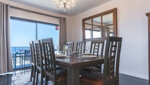 A dining area with a wooden table set for six, surrounded by chairs. - Blue Outlook View by Atlantic Holiday (Água de Pena)