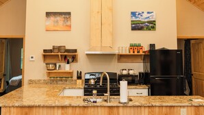 Eine Küche mit Holzschränken, einer Arbeitsplatte aus Granit und einem schwarzen Kühlschrank.