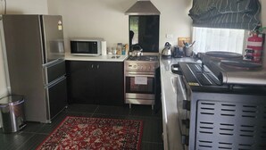 A compact kitchen with a refrigerator, microwave, stove, and oven. - Ruru Retreat - peaceful oasis set off the road, pet friendly! (Coromandel)
