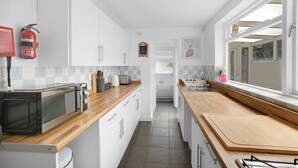 A modern kitchen with white cabinets, a microwave, and a wooden countertop.