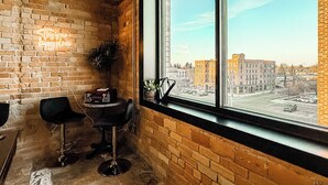 A corner room with a large window, brick walls, and a neon sign.