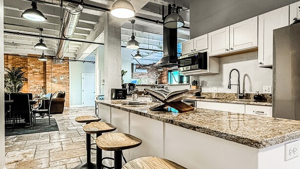 A modern kitchen with a large island, bar stools, and pendant lighting.