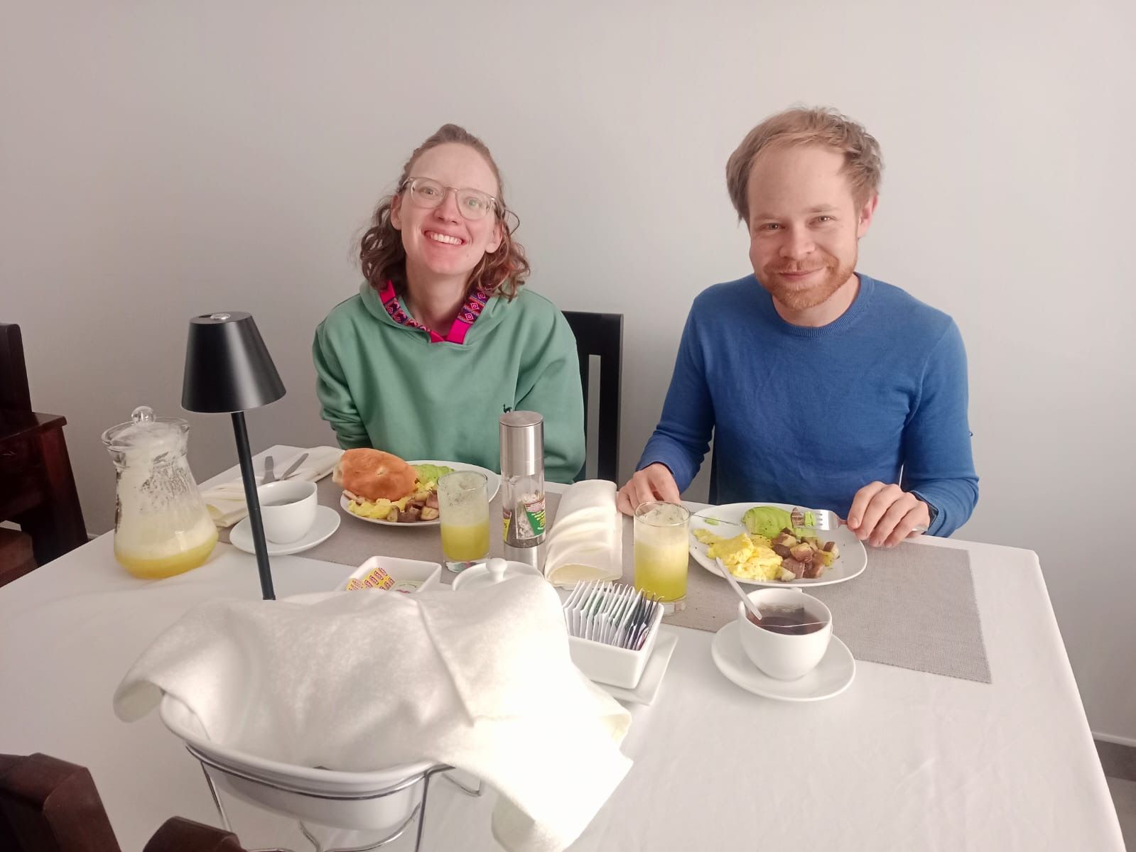 Uma mesa de jantar com pratos de comida, um jarro de suco e uma vela.