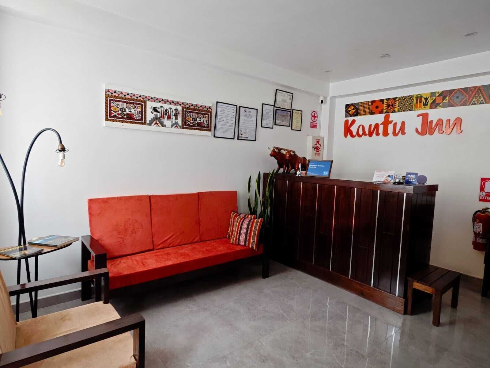 A reception area with a red sofa, a wooden reception desk, framed certificates, and a sign reading "Kantu Inn".