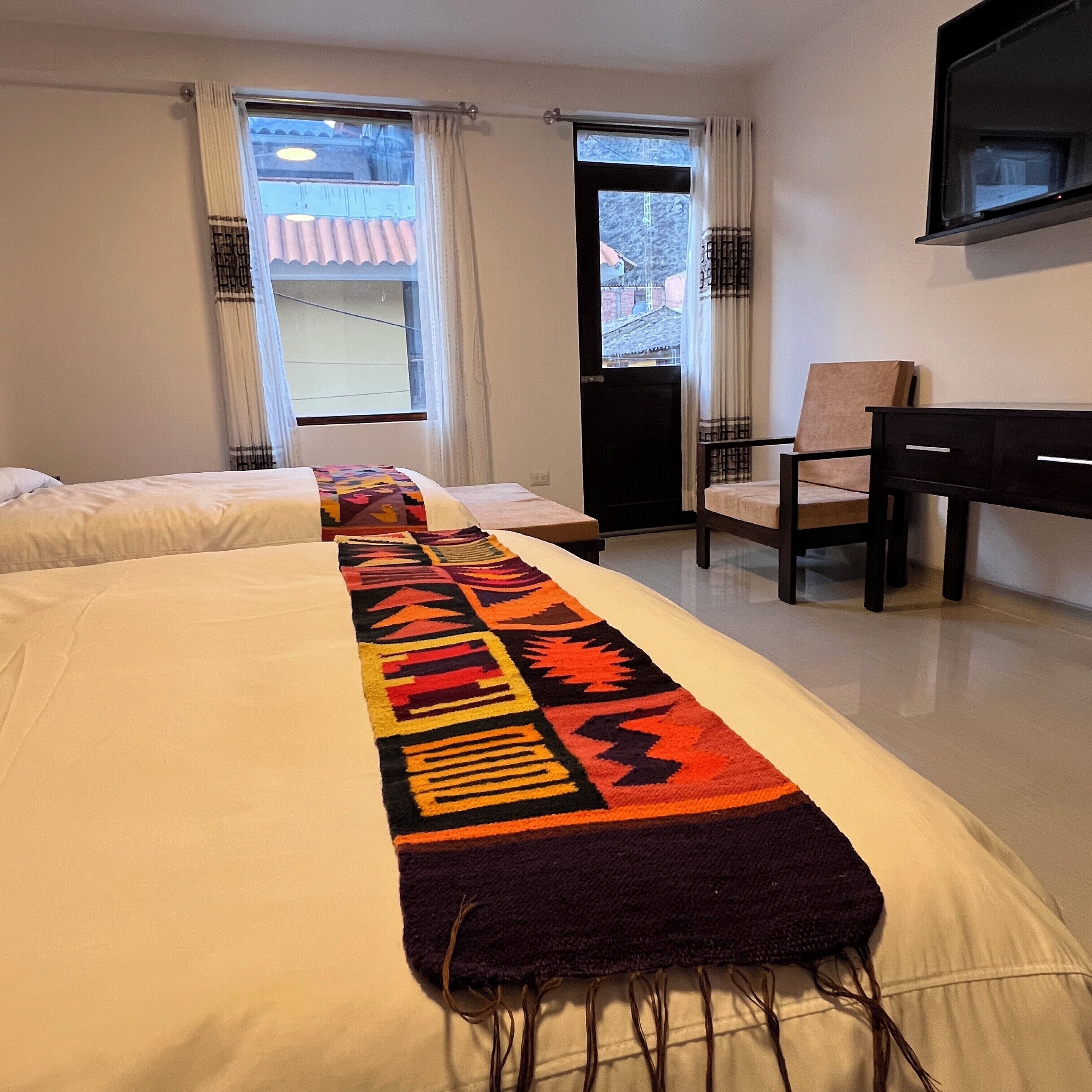 Ein Hotelzimmer mit zwei Betten, einem Schreibtisch und einem Stuhl.
