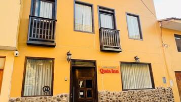 A two-story building with a stone facade, a sign for 'Qata Inn,' and a balcony on the second floor.