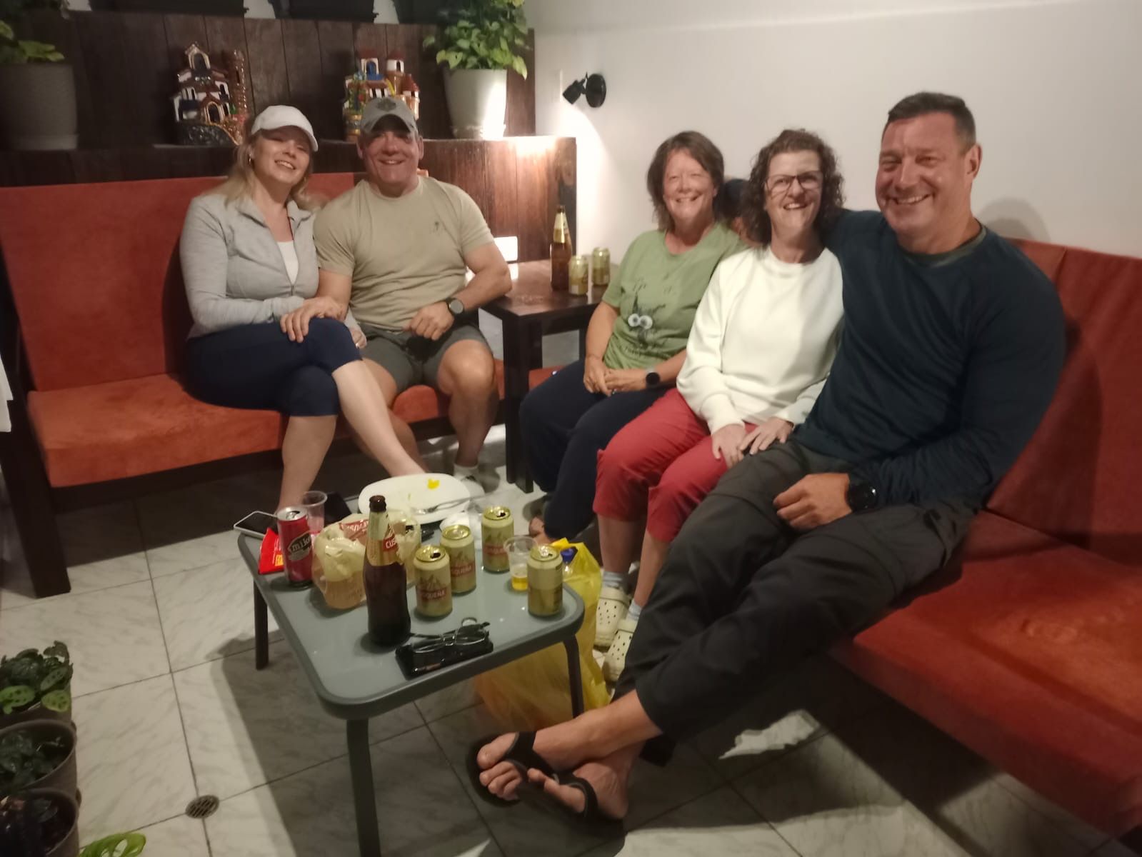 A group of people seated on a couch and a table with various items.