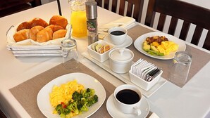 A breakfast setting with bread, eggs, and coffee on a table.