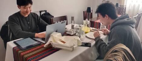 Uma mesa de jantar com um laptop, um smartphone e diversos pratos e copos.