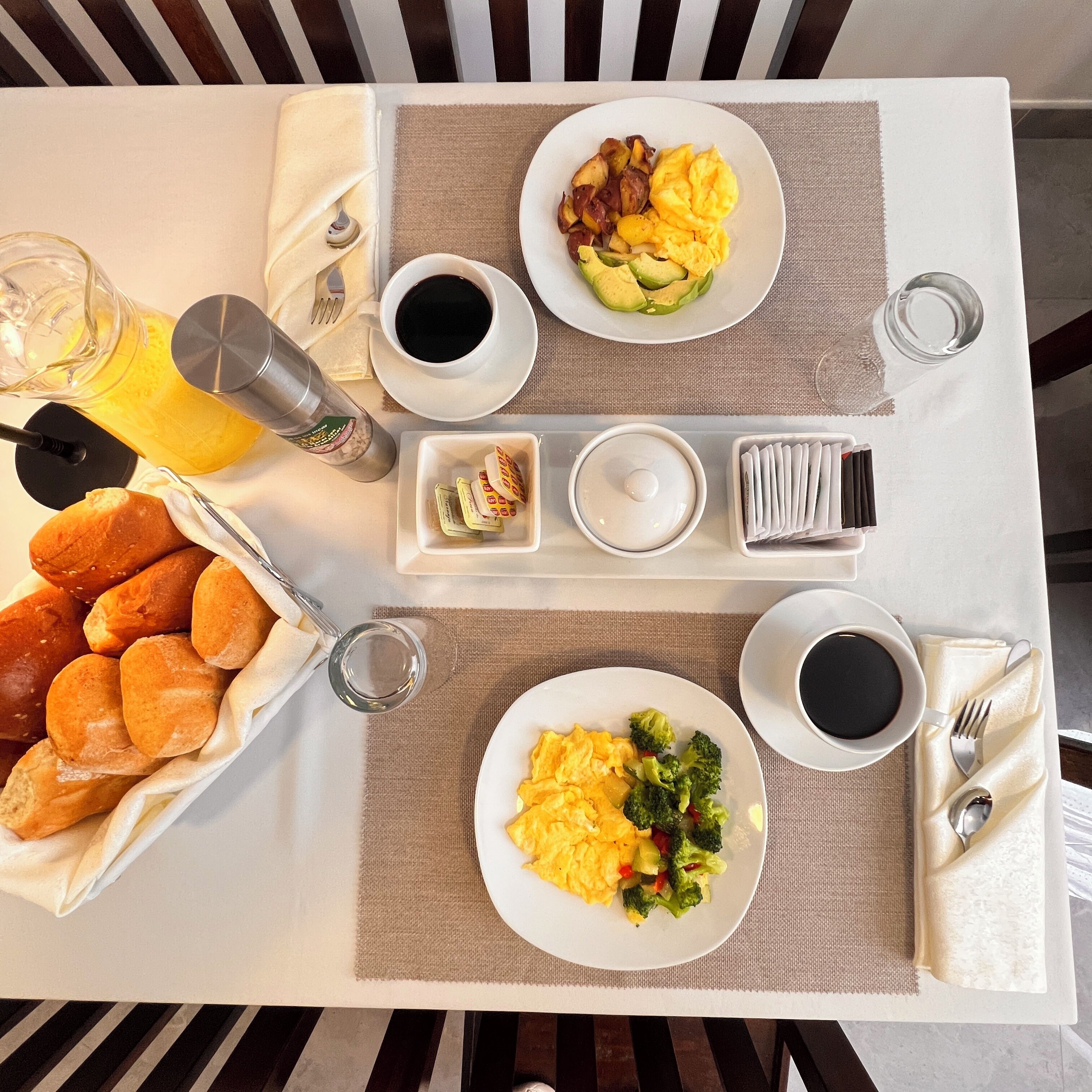 A breakfast tray with scrambled eggs, avocado, bacon, toast, and coffee.